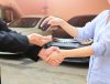 Seorang pria menyerahkan kunci mobil sebagai simbol cara menjual mobil bekas agar cepat laku yang berhasil